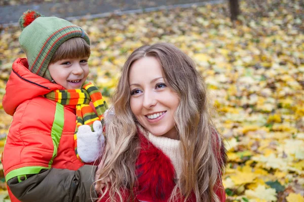 Familia feliz sonriendo y sosteniendo hojas de otoño — Foto de Stock