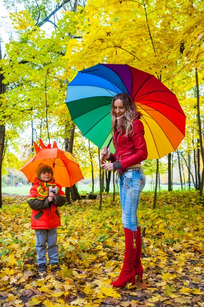 Famiglia felice con ombrelloni colorati nel parco autunnale — Foto Stock