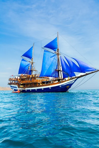 Vintage houten schip met blauwe zeilen — Stockfoto