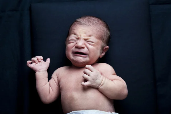 Portret van schattig pasgeboren babymeisje huilen op zwarte achtergrond — Stockfoto