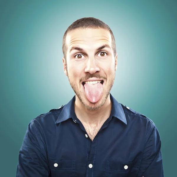 Retrato de un joven hermoso mostrando lengua, expresión de la cara — Foto de Stock