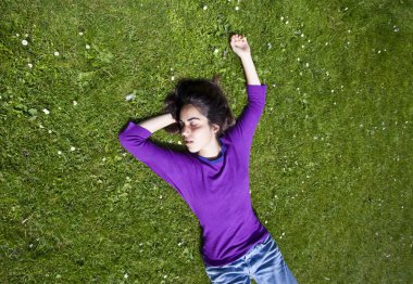 Genç kız çimenlerde dinleniyor.