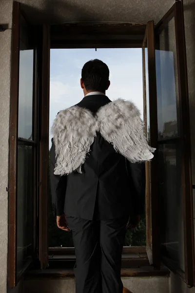 Businessman with angel wings looking through window — Stock Photo, Image