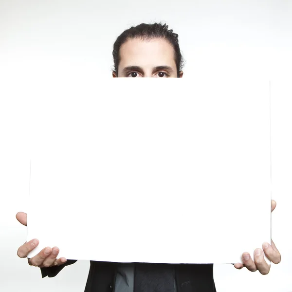 Empresário segurando um sinal em branco na frente oh seu rosto — Fotografia de Stock