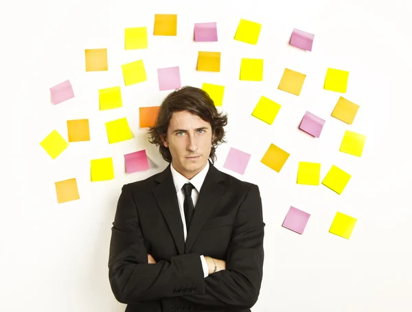 Young businessman with postit reminder notes on the background — Stock Photo, Image