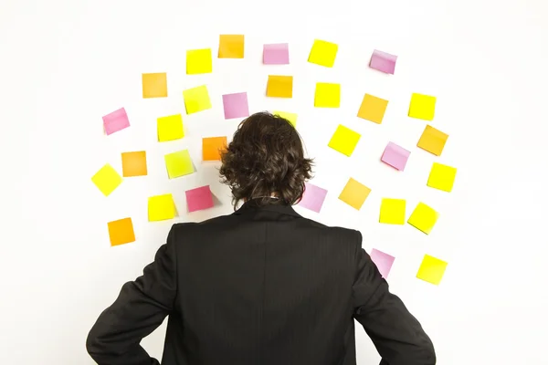 Jonge zakenman met postit herinnering notes op de achtergrond — Stockfoto