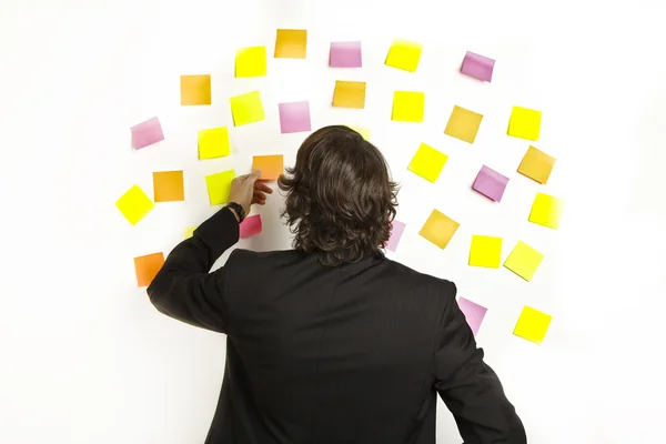 Jovem empresário com notas de lembrete postit no fundo — Fotografia de Stock