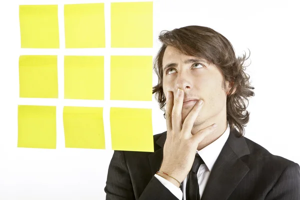 Joven hombre de negocios mirando notas recordatorio postit — Foto de Stock