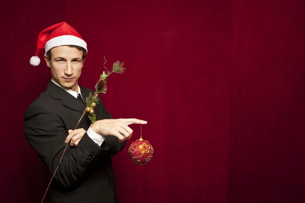 Young funny guy with christmas hat on red velvet background — Stock Photo, Image