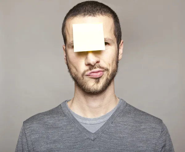 Young man with blank note on the face — Stock Photo, Image