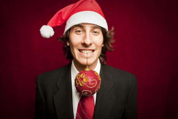 Молодой весельчак в рождественской шляпе на красном фоне — стоковое фото
