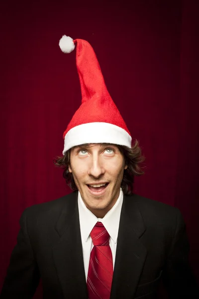 Joven divertido chico con sombrero de Navidad sobre fondo de valvet rojo — Foto de Stock