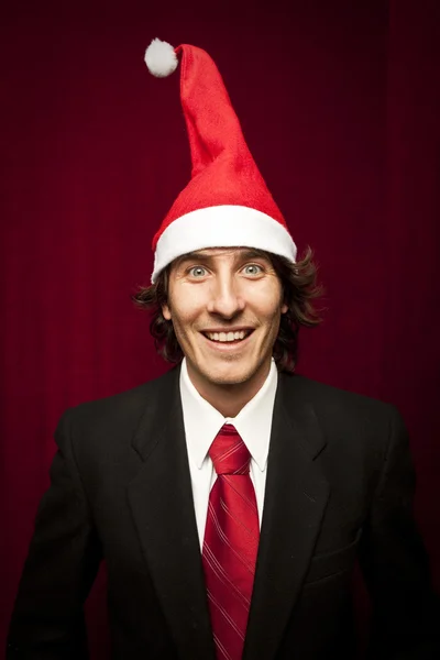 Joven divertido chico con sombrero de Navidad sobre fondo de valvet rojo — Foto de Stock