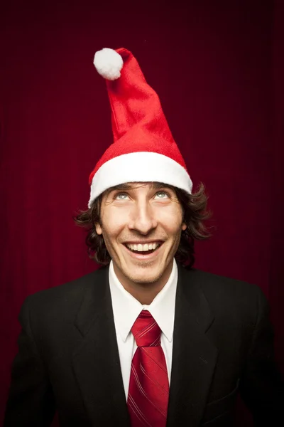 赤 valvet 背景にクリスマスの帽子と変な若い男 — ストック写真