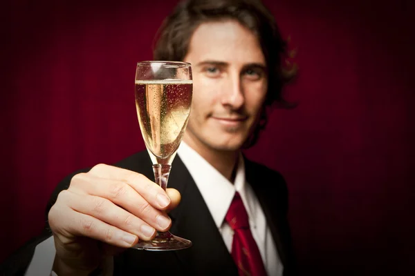 Успешный бизнесмен пьет шампанское против красного цвета. — стоковое фото