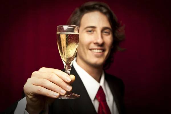 Un homme d'affaires qui trinque avec du champagne contre un bac rouge — Photo