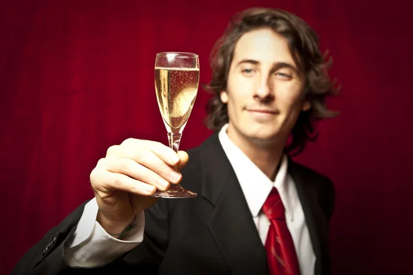 Успешный бизнесмен пьет шампанское против красного цвета. — стоковое фото