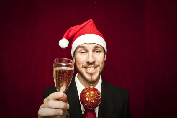 Junger lustiger Kerl mit Weihnachtsmütze auf rotem Ventilhintergrund — Stockfoto