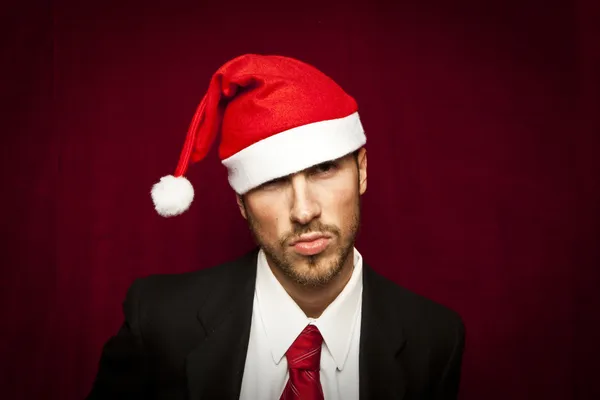 Junger lustiger Kerl mit Weihnachtsmütze auf rotem Ventilhintergrund — Stockfoto