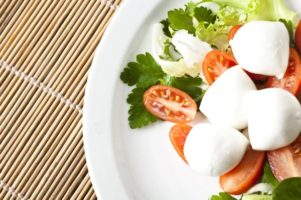 Mozzarella und Tomaten auf grünem Salat, italienisches Essen — Stockfoto
