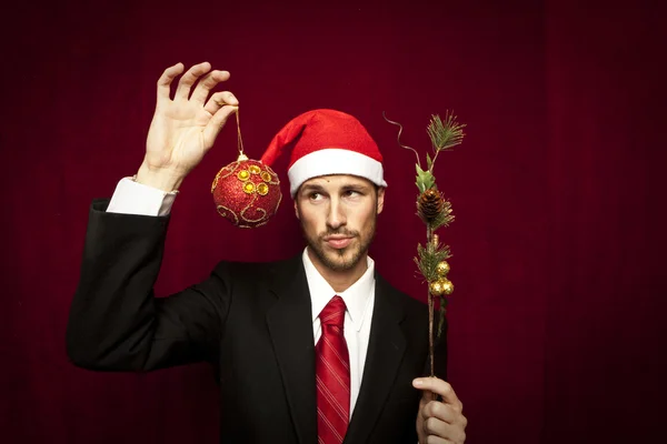 Young funny guy with christmas hat on red velvet background — Stock Photo, Image