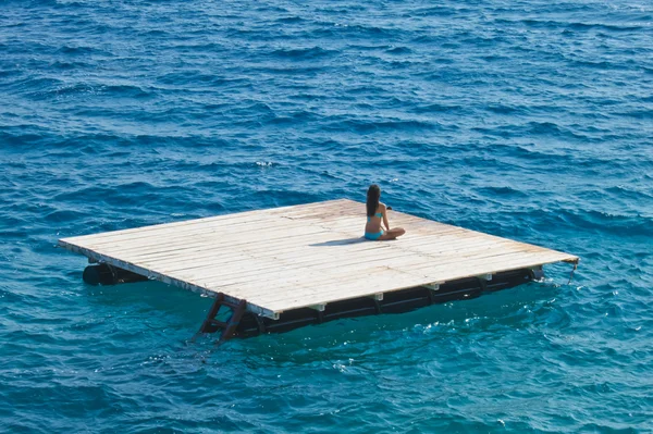 Jovem relaxante em uma jangada de madeira no mar — Fotografia de Stock
