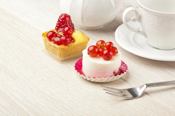 Pastelaria de frutas pouco bolo com xícara de chá na mesa de madeira branca — Fotografia de Stock