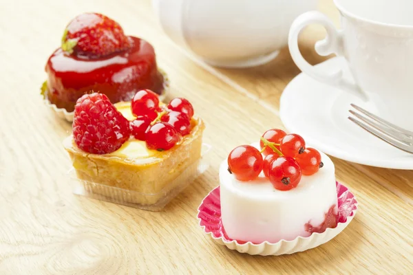 Pastelaria de frutas pouco bolo com xícara de chá na mesa de madeira — Fotografia de Stock