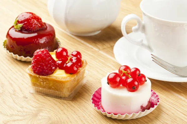 Pastelaria de frutas pouco bolo com xícara de chá na mesa de madeira — Fotografia de Stock