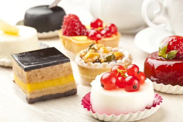 Különböző típusú gyönyörű sütemények, kis színes édes sütemények — Stock Fotó