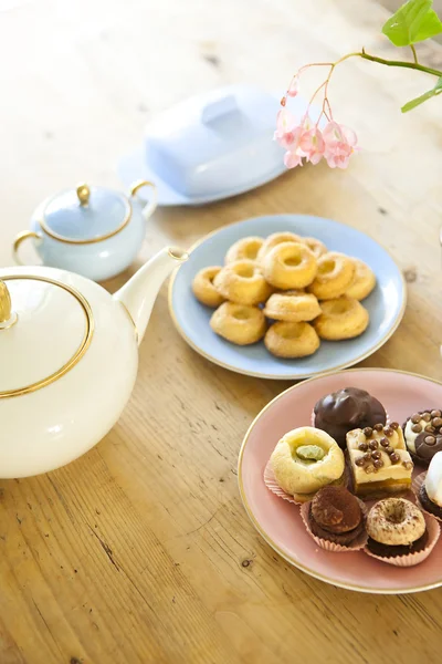 Teller mit Gebäck und Keksen und Teekanne auf Holztisch — Stockfoto