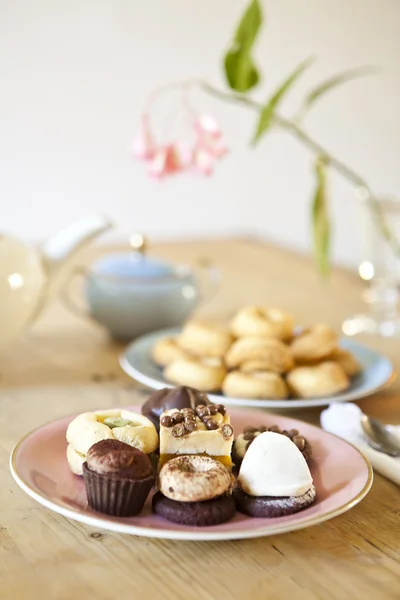 Pratos de doces e biscoitos e panela de chá na mesa de madeira — Fotografia de Stock