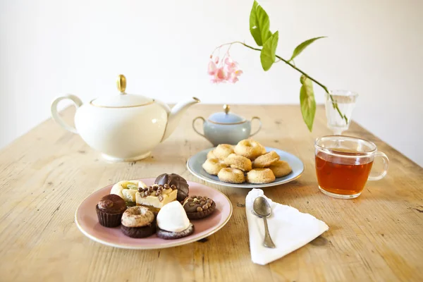 Pratos de doces e biscoitos e panela de chá na mesa de madeira — Fotografia de Stock