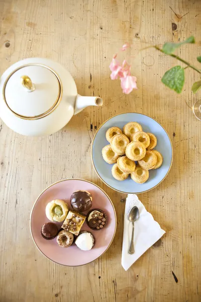 Piring kue-kue dan biskuit dan teko teh di meja kayu — Stok Foto
