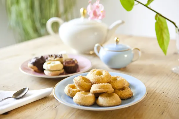 Assiettes de pâtisseries et biscuits et théière sur table en bois — Photo