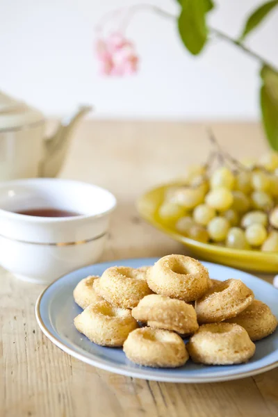 Pratos de doces e biscoitos e panela de chá na mesa de madeira — Fotografia de Stock