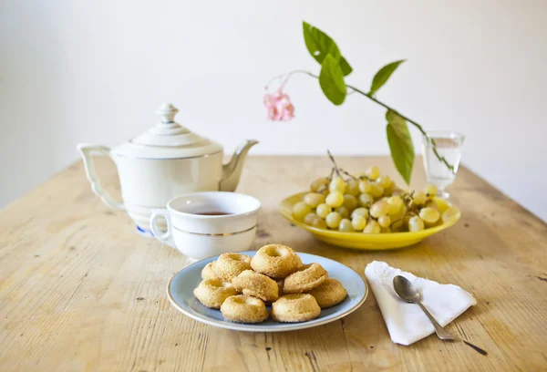 Platen van gebakjes en koekjes en theepot op houten tafel — Stockfoto