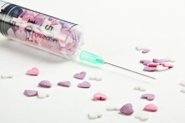 kalp şeklinde şeker beyaz bir arka planda şırınga dolu