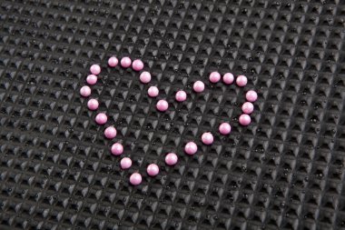 Lastik siyah arka plan üzerine şeker ile yapılan kalp şekli