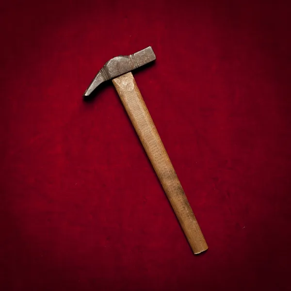 Vieux marteau de traîneau avec poignée en bois sur fond rouge — Photo