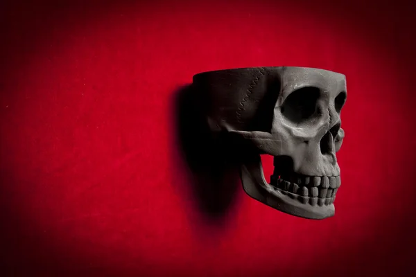 Preto assustador humano crânio no vermelho veludo fundo — Fotografia de Stock