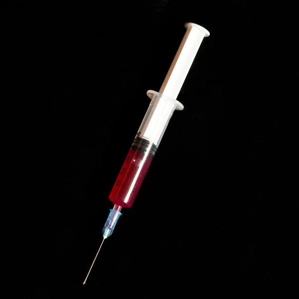 Syringe with blood isolated on black — Stock Photo, Image