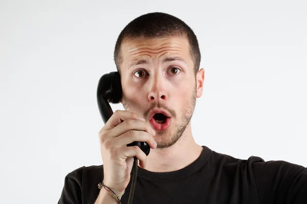 Молодой человек с эмоциями у телефона — стоковое фото