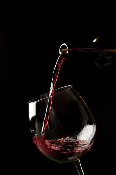 Salpicadura de vino tinto en una copa sobre fondo negro . — Foto de Stock