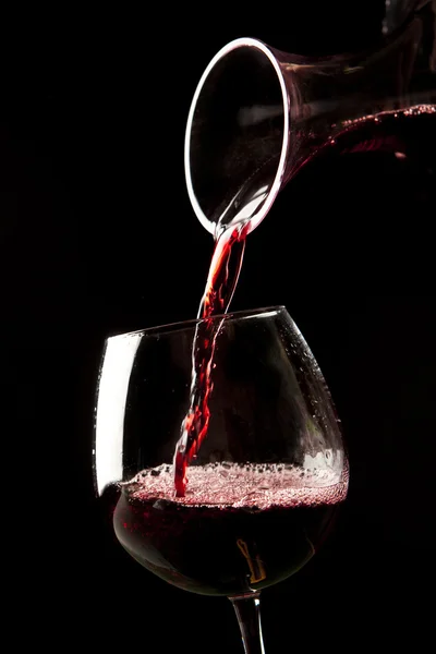 Красное вино брызги на стакан на черном фоне . — стоковое фото