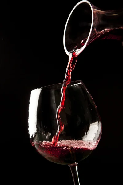 Červené víno splash na sklenici na černém pozadí. — Stock fotografie