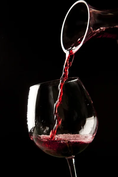 Red wine splash on a glass on black background. — Stock Photo, Image