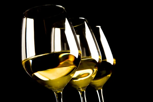 Три бокала белого вина на черном фоне — стоковое фото