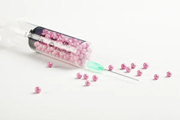 Syringe filled with pink candy on a white background — Stock Photo, Image