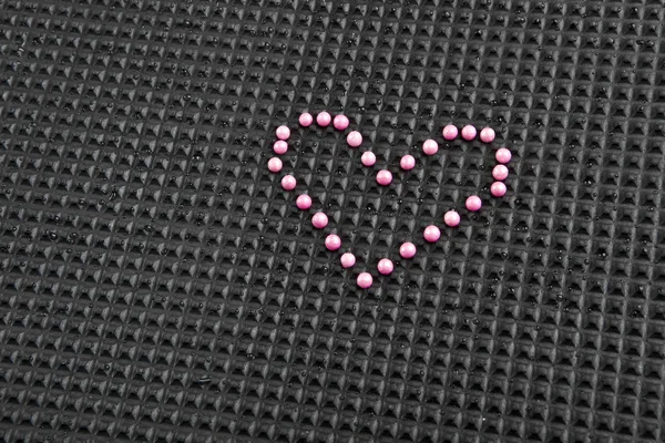 Heart shape made with candy on rubber black background — Stock Photo, Image
